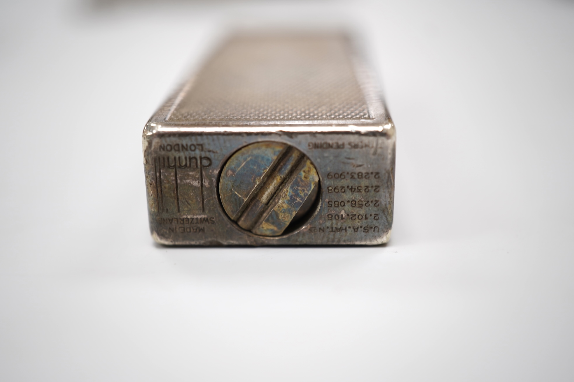 An early 20th century white metal oval locket, 40mm, on a silver chain, a silver plated Dunhill lighter, in Dunhill box, a white metal cased manual wind wrist watch and a tortoiseshell purse.